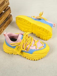 Close-up van levendige roze, blauwe en gele mesh dad-sneakers met dikke zool op neutrale vloer