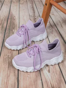 Seitenansicht lavendelfarbener atmungsaktiver Fly-Knit-Damen-Sneaker auf Holzboden