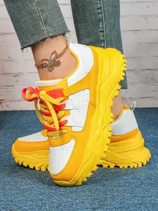 Vibrant yellow and white chunky platform sneakers shown with a decorative butterfly anklet