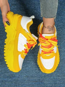 Detailed view of yellow chunky sneakers with white panels and vibrant orange laces