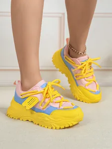 Gedetailleerd zijaanzicht van kleurrijke platform sneakers met gele veters en mesh