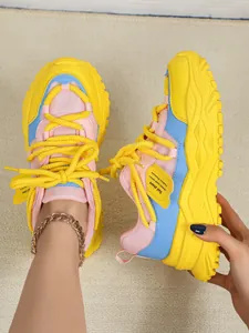 Close-up van kleurrijke dad-sneakers met roze mesh en opvallende gele accenten.