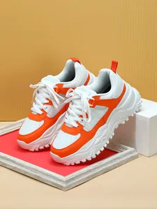 Detailed side view of orange and white chunky platform sneakers in a studio setting