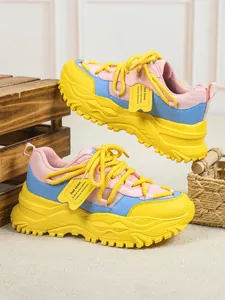 Detailweergave van kleurrijke chunky dad-sneakers met roze, blauwe en gele accenten