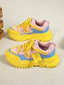 Close-up van kleurrijke chunky sneakers met gele, roze en blauwe mesh panelen.