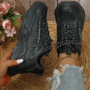 Detailopname van stijlvolle zwarte chunky sneakers met dikke zool en ademend mesh materiaal
