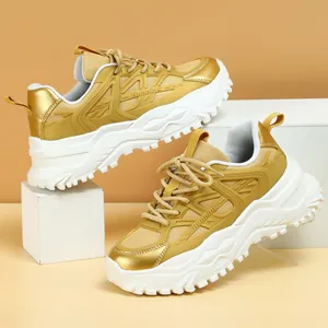 Gedetailleerd zijaanzicht van gouden chunky sneakers met ademende mesh-inzetstukken.