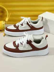 Vista lateral de zapatillas casuales marrones y blancas con suelas gruesas y cordones blancos