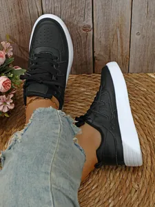 Elegantes zapatillas negras de suela gruesa con vaqueros rotos sobre una alfombra tejida