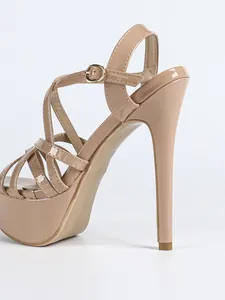 Close-up of elegant nude patent leather high-heeled sandals with crossover straps and platform