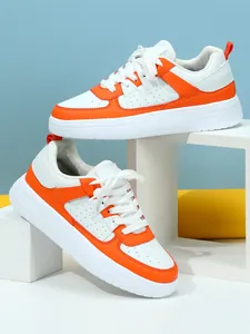 Vista detallada de zapatillas de plataforma naranja y blanco en soportes geométricos blancos