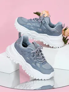 Gedetailleerde weergave van ademende blauw-witte dad-sneakers met een dikke zool.