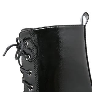 Close-up detail of black patent leather lace-up platform boots with metal eyelets