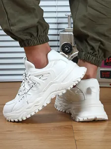 Gedetailleerd zijaanzicht van witte chunky sneakers met plateauzool en cargo broek.