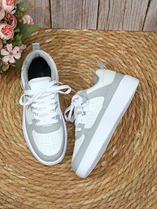 Vista superior y lateral de zapatillas con plataforma grises y blancas sobre estera de paja