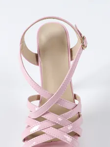 Detailed macro view of elegant pink patent leather platform sandals featuring crisscross straps