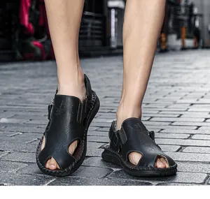 Sandalias de cuero negro para hombre con aberturas transpirables en suelo de piedra.