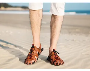 Close-up detail of brown leather men's hollow beach sandals worn on a sandy seashore
