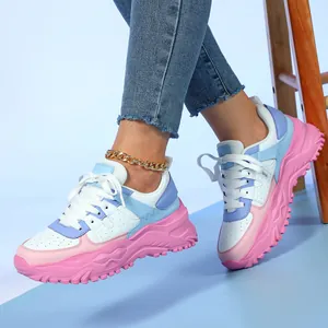 Fashionable thick-sole sneakers in pastel pink and blue worn with denim jeans.