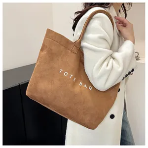 Détail d'un sac cabas vintage en daim marron avec inscription TOTE BAG en blanc