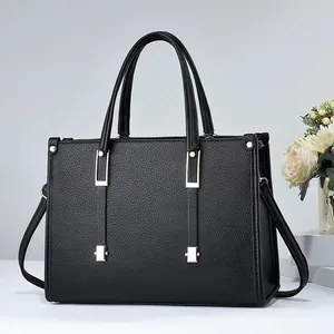 Elegante bolso de mano de piel texturizada negra con detalles metálicos dorados modernos.