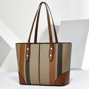 Large striped tote bag with elegant brown leather handles and textured fabric finish.