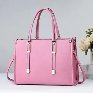Vista detallada de un bolso shopper de cuero granulado rosa con detalles dorados.