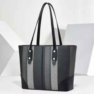 Front view of a striped tote bag with elegant black leather straps and gold rivets