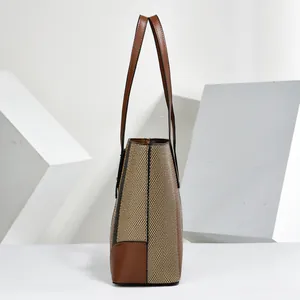 Side view of a stylish textured striped tote bag with brown handles and corner details.