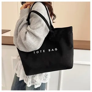 Vue détaillée du sac cabas vintage en daim noir avec inscription TOTE BAG blanche