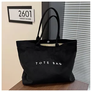 Grand sac cabas en daim noir vintage avec inscription TOTE BAG dans un cadre chaleureux.