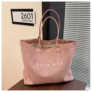 Détail d'un sac cabas en daim rose avec lettrage TOTE BAG blanc imprimé dessus.