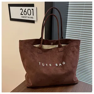 Détail d'un sac cabas en daim marron vintage avec l'inscription TOTE BAG sur un bureau