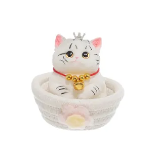 Adorable white cat squeeze toy wearing a crown inside a decorative woven basket