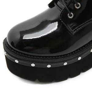 Gros plan de bottines à plateforme en cuir verni noir avec détails de clous argentés
