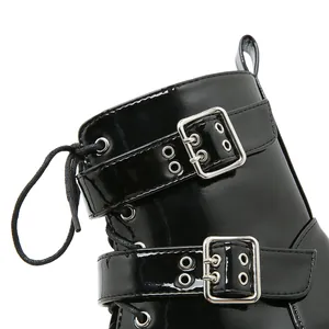 Détail d'une botte en cuir verni noir présentant des boucles argentées et des lacets
