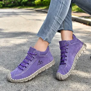Detailed view of purple hand-stitched suede loafers with laces in outdoor light