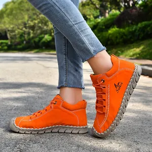 Close-up detail of vibrant orange hand-stitched leather loafers on an outdoor asphalt road.