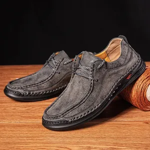 Detail view showing handmade grey leather loafers with decorative stitching and laces