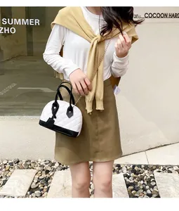 Model carrying a stylish black and white quilted shell handbag with gold chain