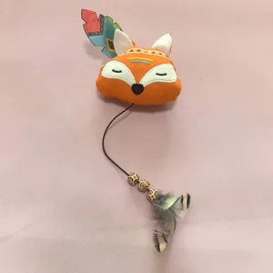 Détail d'un jouet pour chat renard en peluche avec plumes et perles.