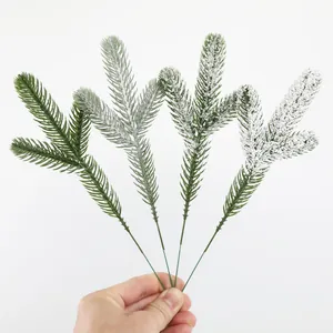Detailed view of four artificial pine needle branches with varying snow flocking.