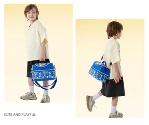 Sac à bento isotherme bleu avec motifs de dessins animés pour enfants, porté par un jeune garçon