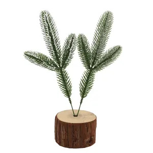 Close-up of artificial three-pronged pine needles with snow effect on wooden base