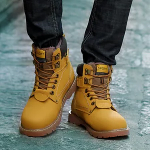 Botas Martin clásicas de cuero amarillo con vaqueros azules sobre suelo de piedra