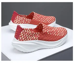 Vista detallada de mocasines tejidos a mano naranja para mujer con suelas blancas