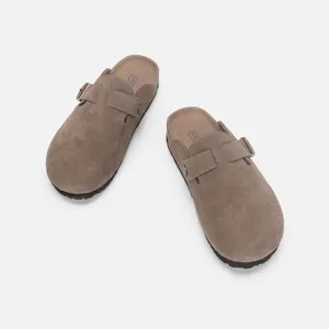 Vue détaillée des sabots en daim taupe avec boucle métallique réglable et semelle en liège