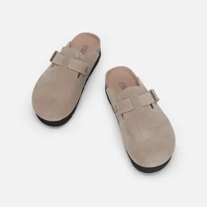 Détail de sabots en daim beige avec une semelle souple et une boucle ajustable