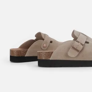 Vue détaillée des sabots en daim taupe avec semelle en liège naturel et boucle en cuivre.