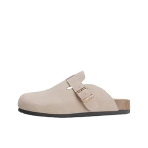 Sabots classiques en daim beige avec boucle métallique réglable sur fond blanc uni